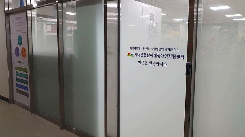 센터 입구. 유리문에 '방문을 환영합니다'와 센터 로고, 미션·비전 안내판이 붙어 있다.