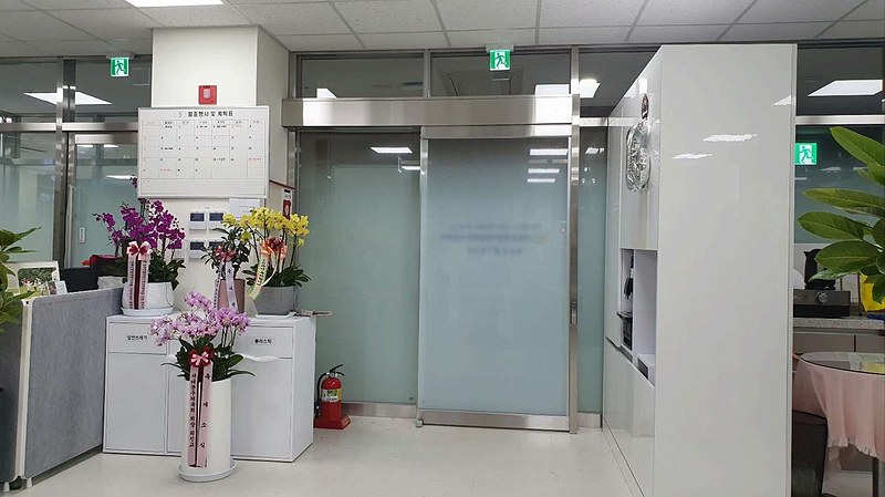 센터 현관 및 안내 공간. 월중행사 계획표와 자동문, 소화기가 설치되어 있다.